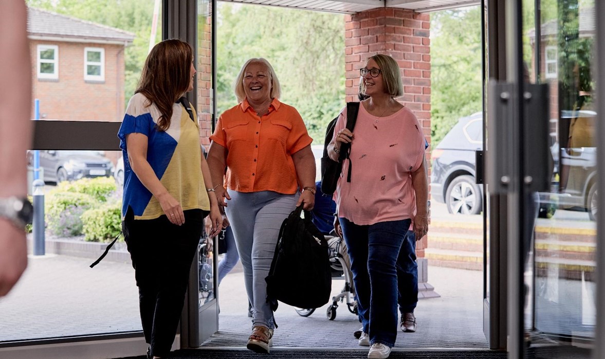 Motability Foundation colleagues are walking into their office building smiling and talking. 