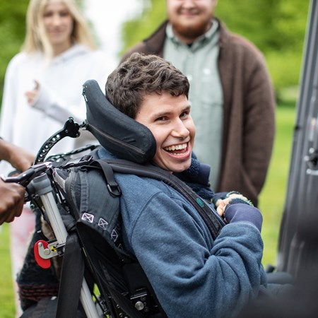 A boy in a wheelchair is smiling.