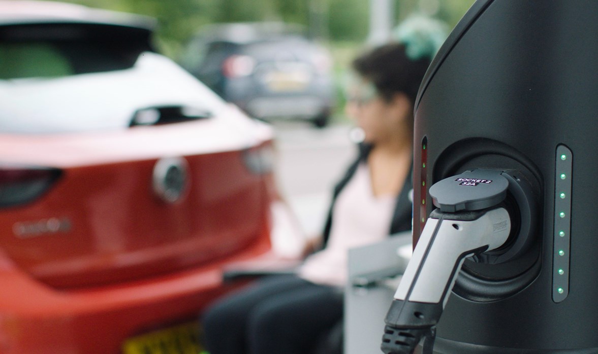 Electric vehicle charging-point and a lady next to a car